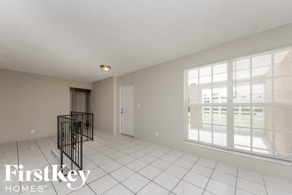 an empty living room with a staircase and a large window