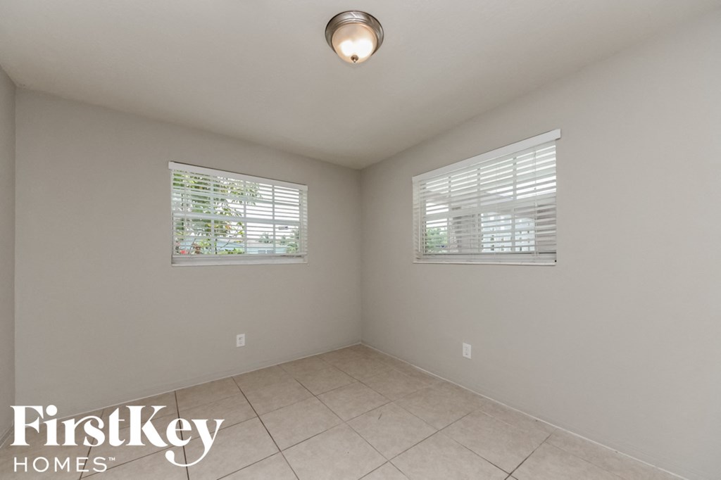 an empty room with two windows and a tile floor