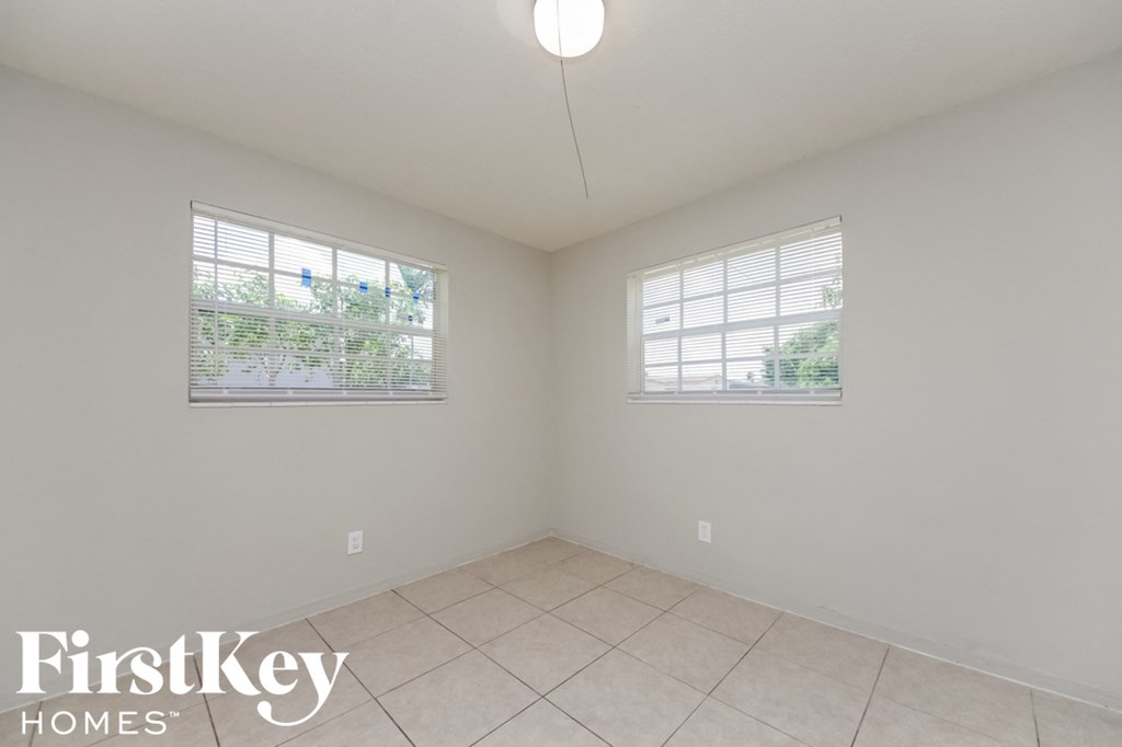 an empty room with two windows and a tile floor