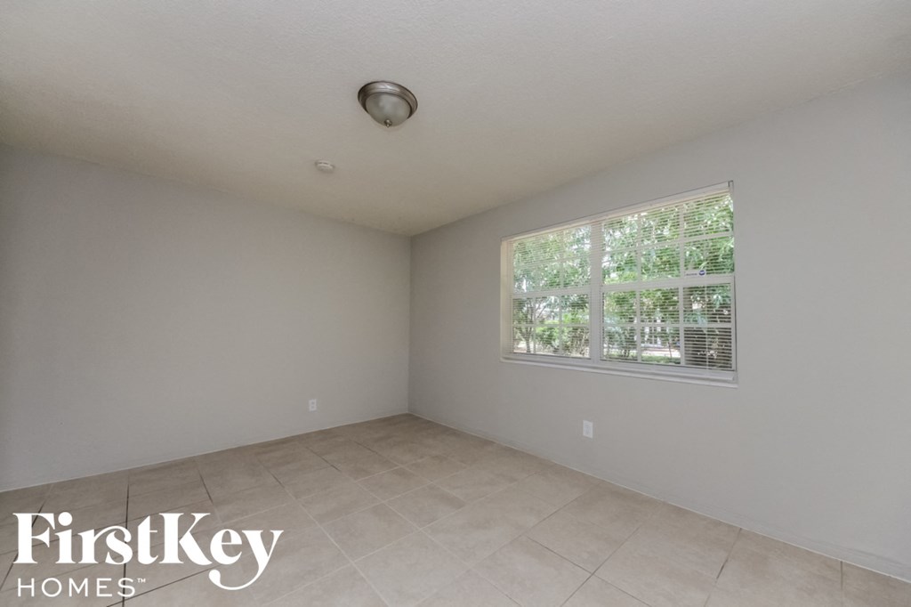 an empty room with a large window and tiled floors