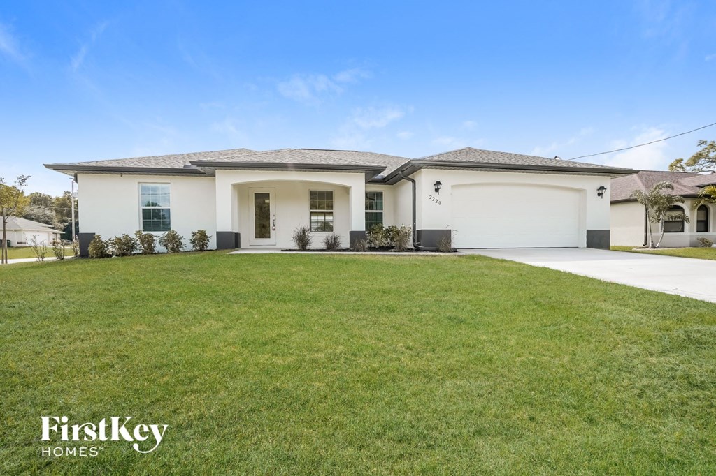 A white house with a black roof and a garage door is for sale.