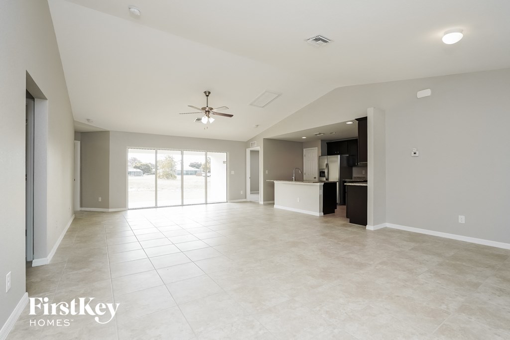 A spacious living room with a ceiling fan and sliding glass doors.