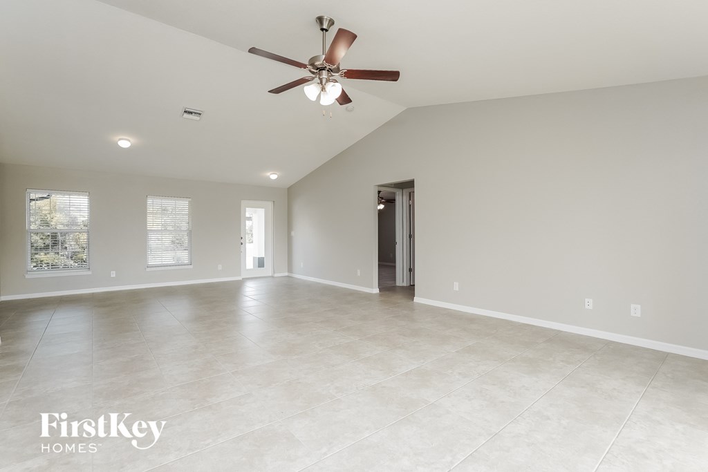 A spacious room with a ceiling fan and lighting fixtures.