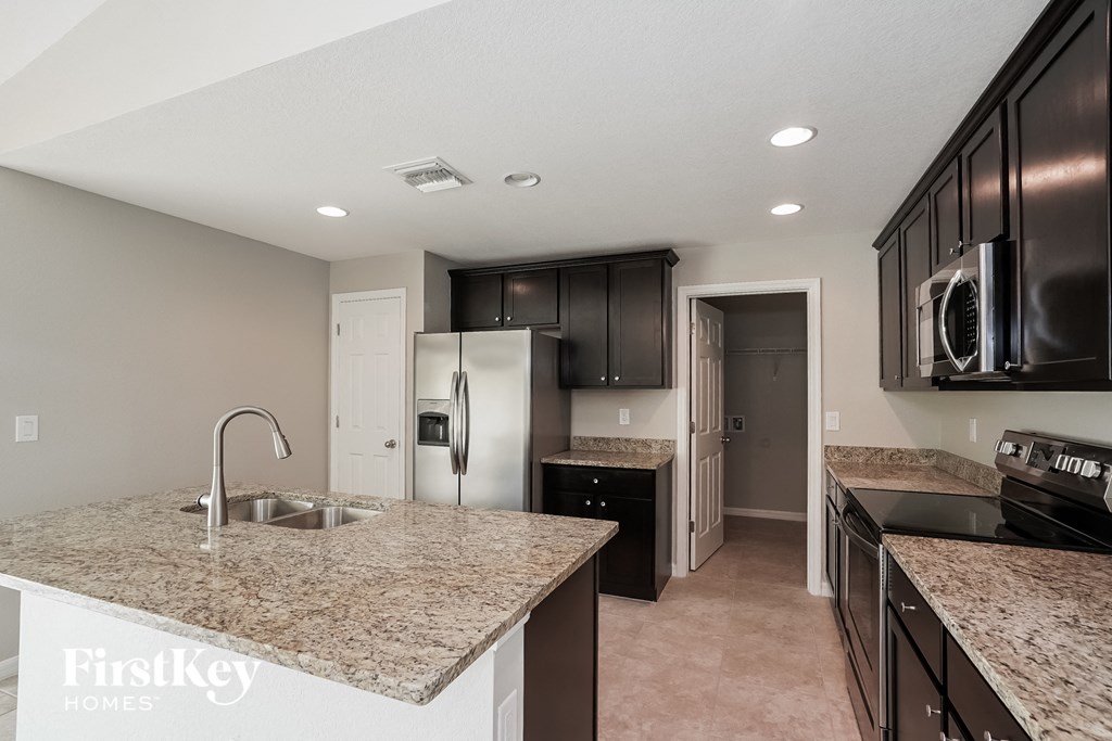 A kitchen with granite countertops and black appliances.