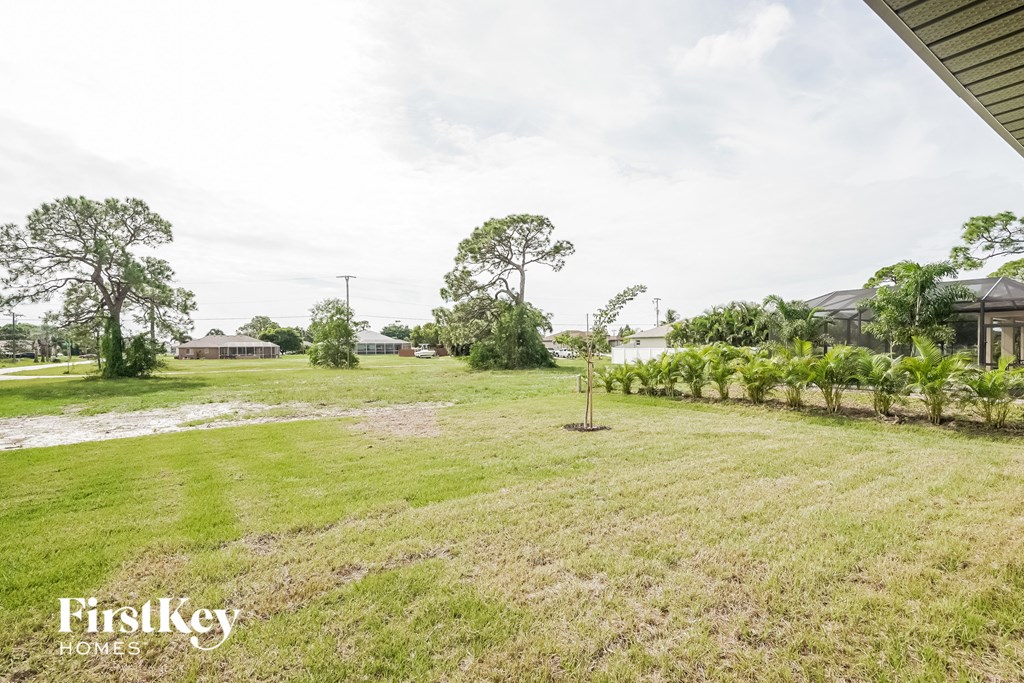 A grassy field with trees and a house in the distance.