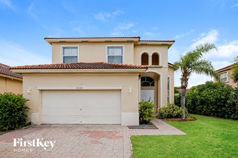 A two-story house with a garage and a palm tree in front.