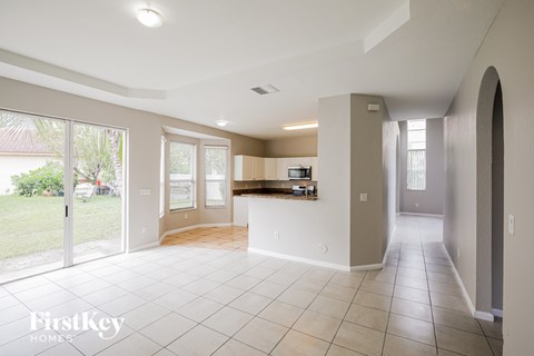 A spacious, empty room with a kitchen area in the background.