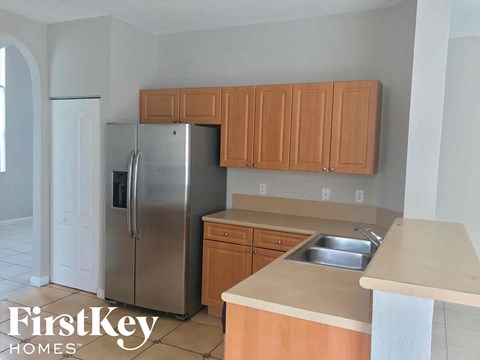 A kitchen with wooden cabinets and a stainless steel refrigerator.