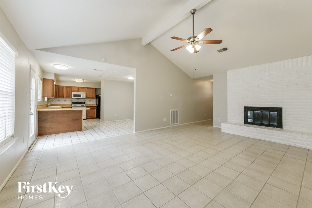 A spacious living room with a fireplace and a ceiling fan.