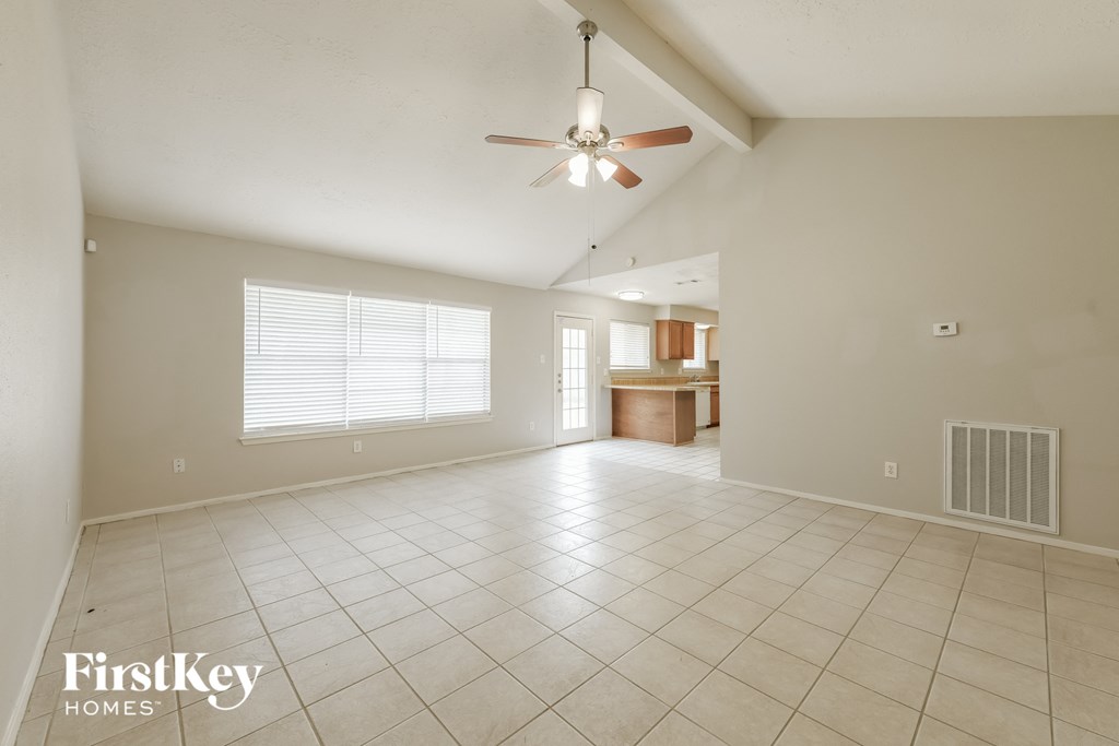 A spacious room with a ceiling fan and a window with blinds.