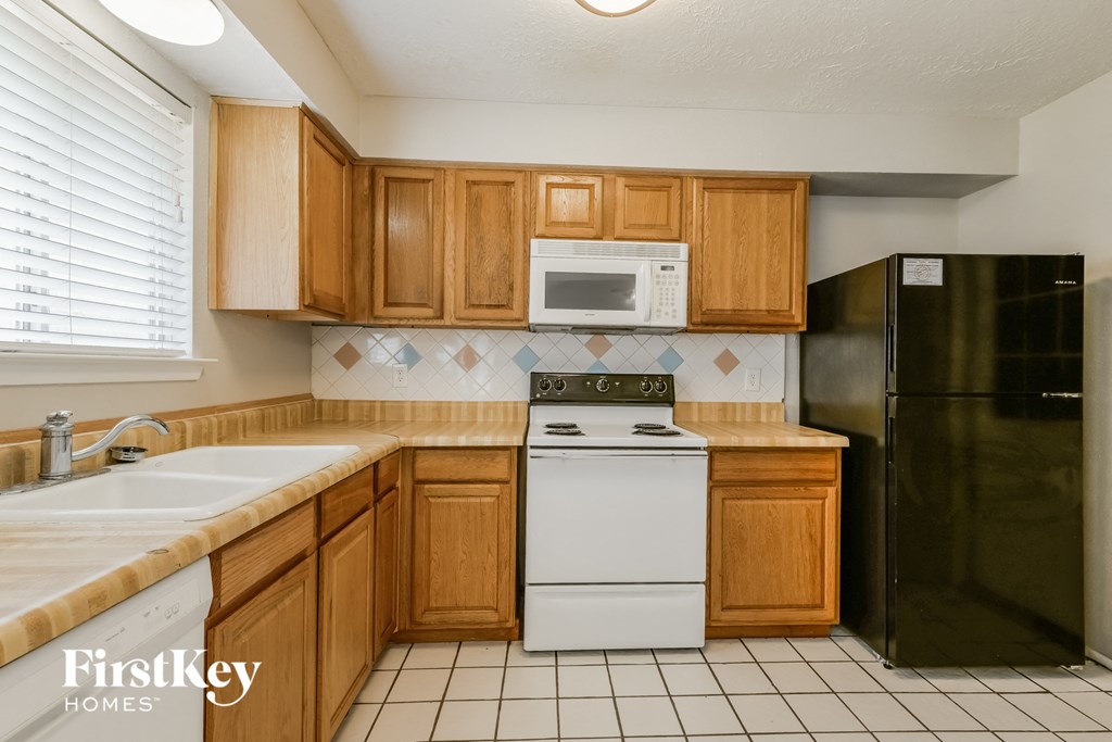 A kitchen with wooden cabinets and a black refrigerator.