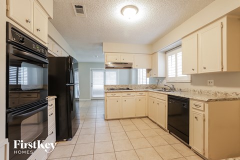 A kitchen with a black fridge and white cabinets.