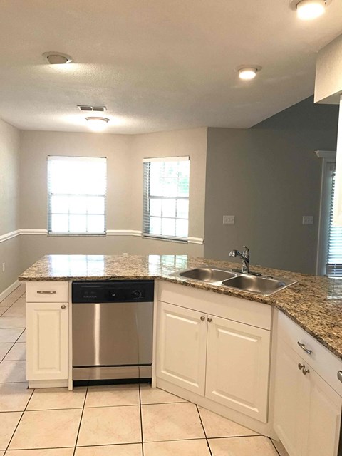 A kitchen with a granite countertop and white cabinets.