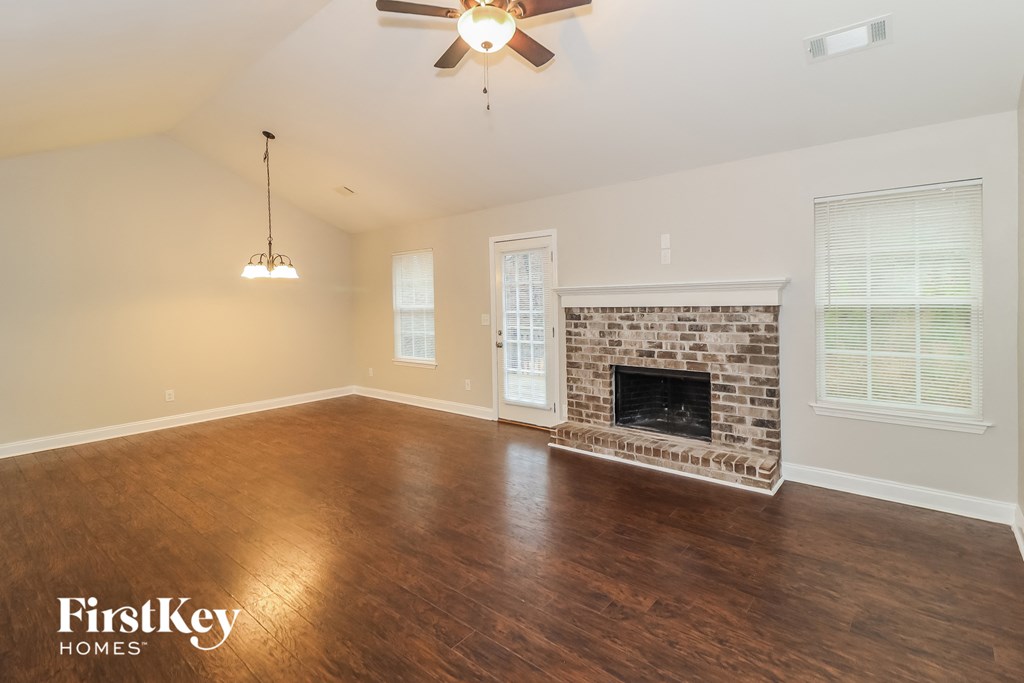 a living room with a brick fireplace and a ceiling fan