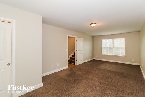 a living room with carpet and a door to a staircase