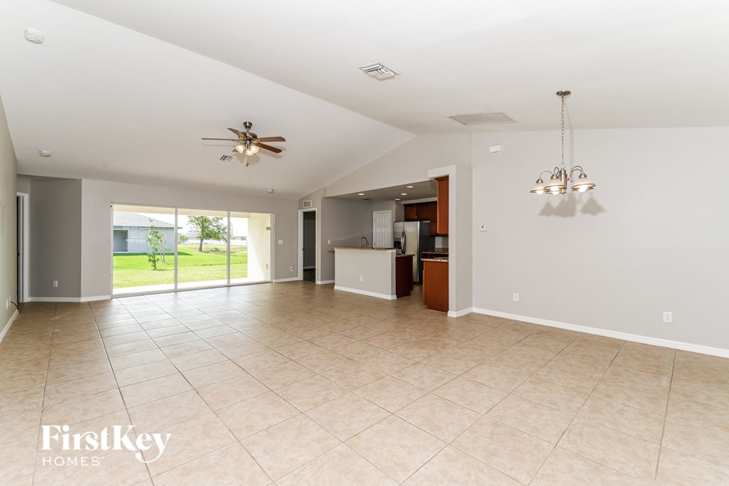 a large empty living room with a kitchen and a ceiling fan