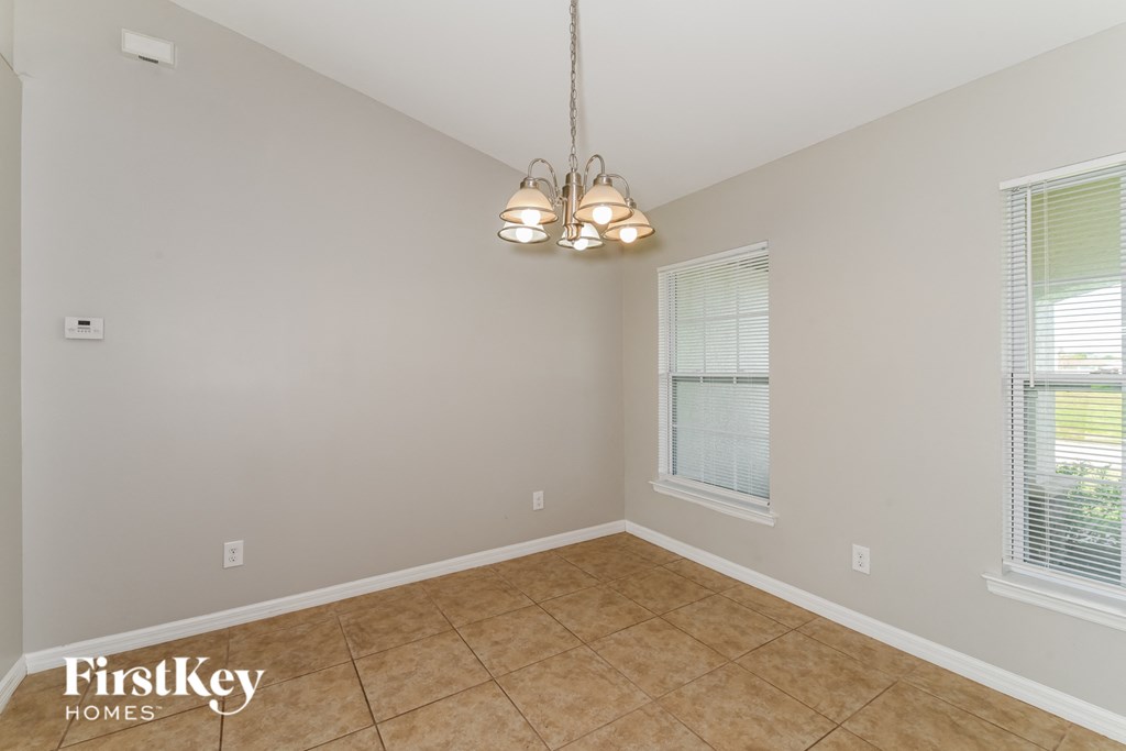 a dining room with a chandelier and a tiled floor