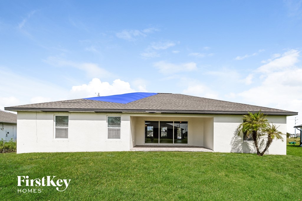 a white house with a blue roof and a palm tree