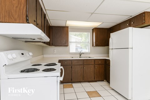 A kitchen with a white stove and refrigerator from FirstKey Homes.
