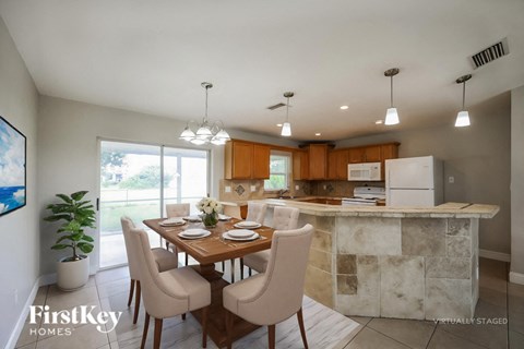 A dining room with a table set for two and a kitchen in the background.