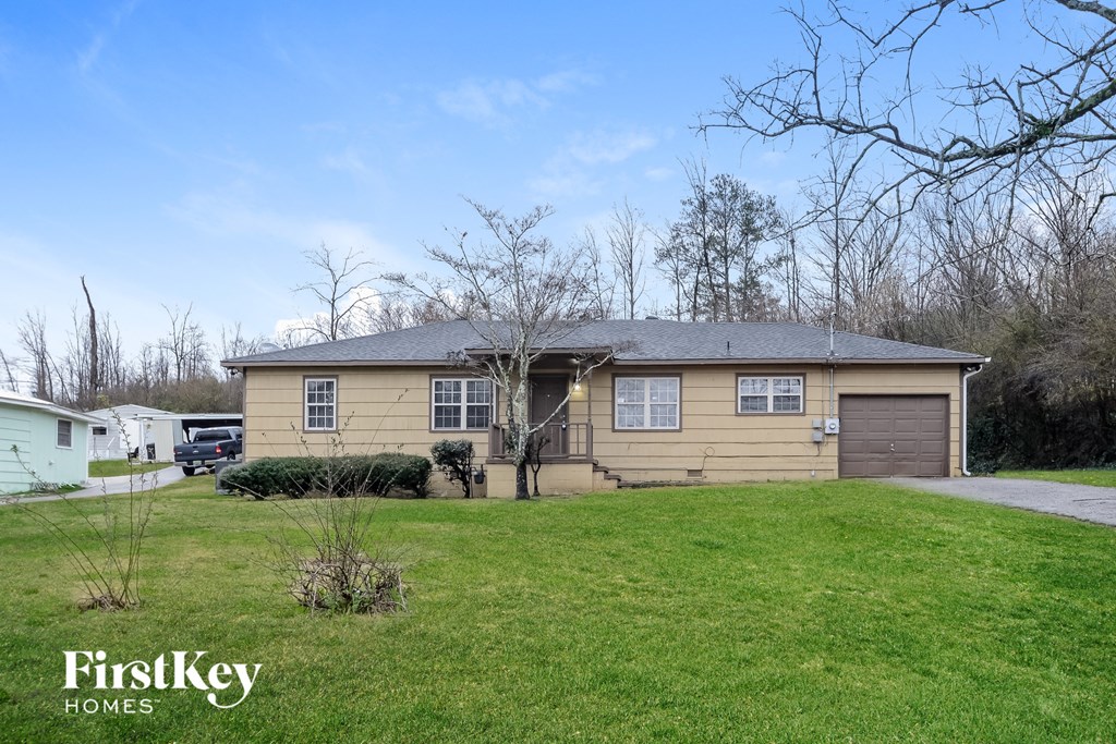 a yellow house with a driveway and a green lawn