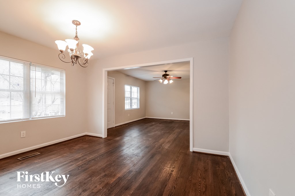 an empty living room with wood floors and a ceiling fan