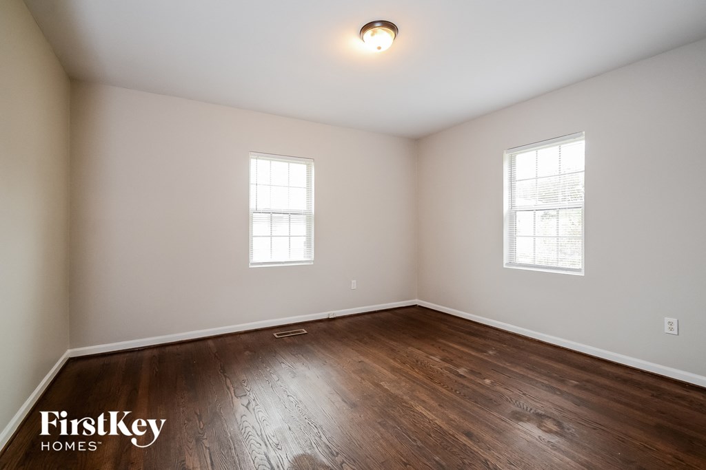 the living room of a home with wood flooring and two windows