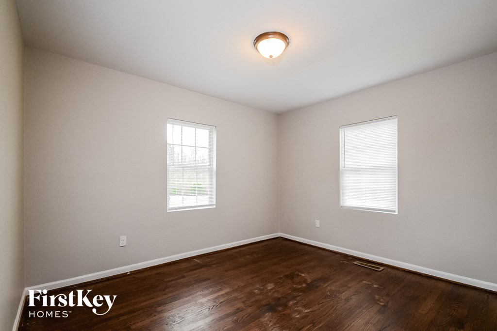 the living room of a home with wood flooring and two windows