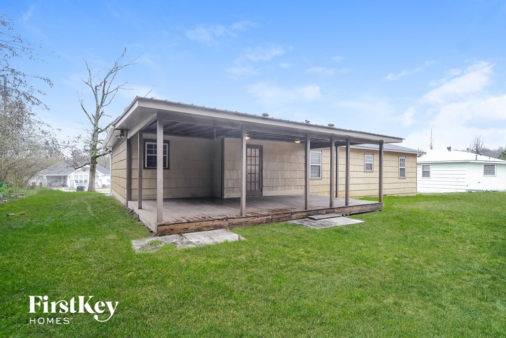 a small wooden cabin with a porch in a grass field