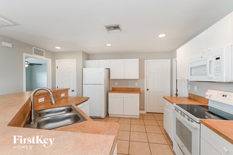 a kitchen with white cabinets and appliances and a sink