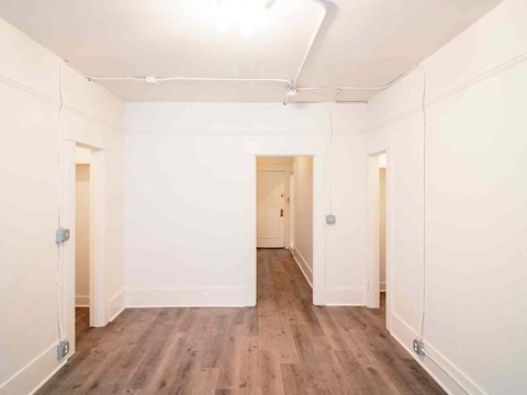 A long, narrow room with wooden floors and white walls.