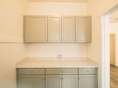 A kitchen with a marble countertop and grey cabinets.