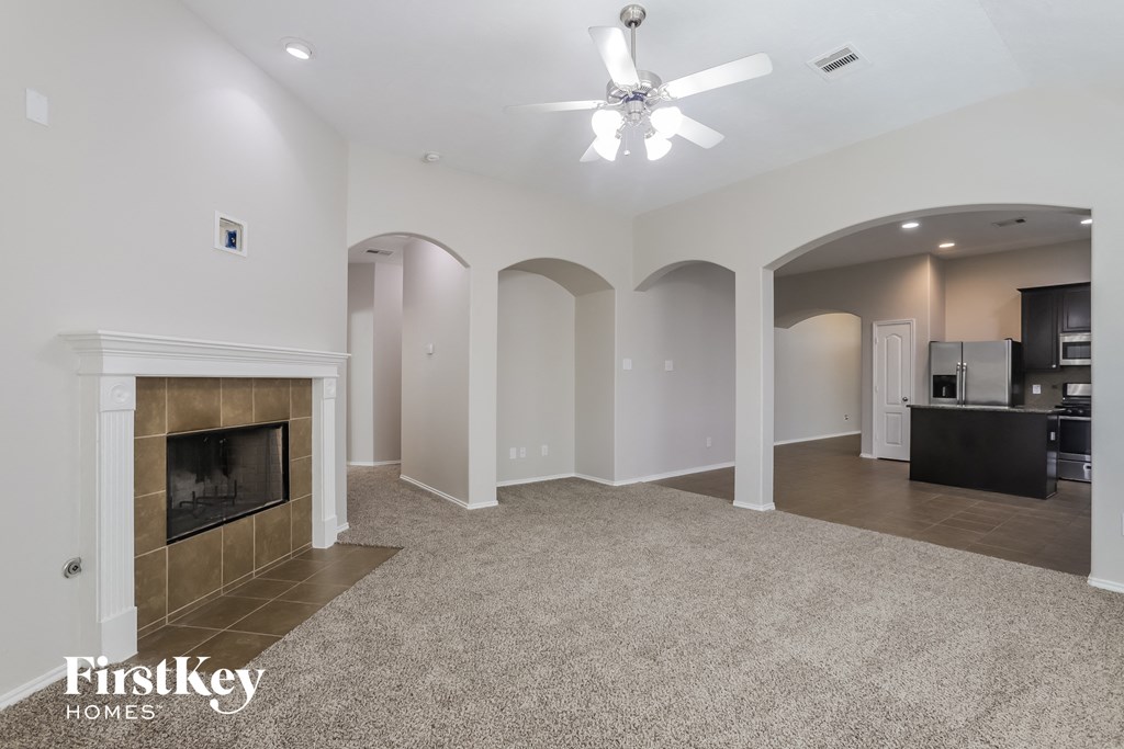 a large living room with a fireplace and a ceiling fan