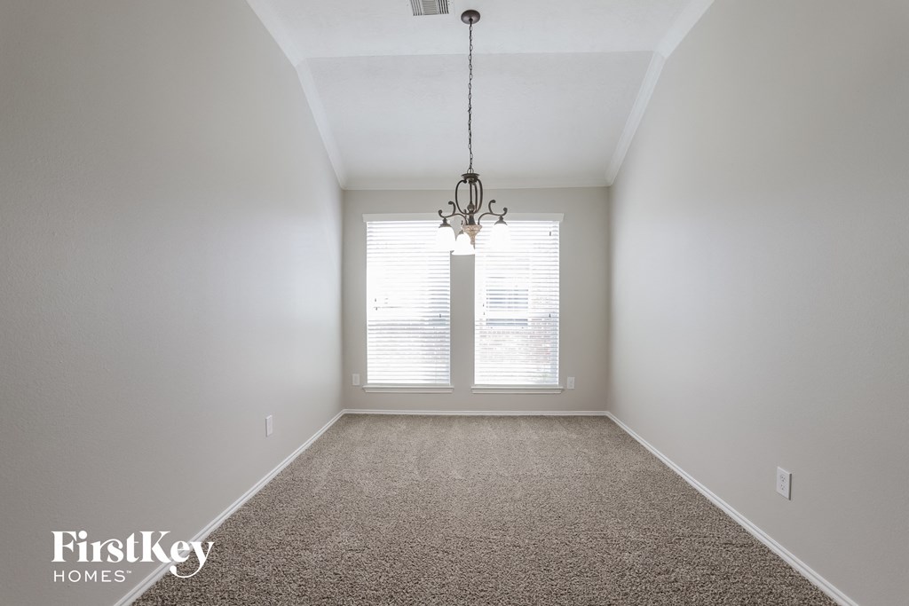 an empty living room with a window and a chandelier