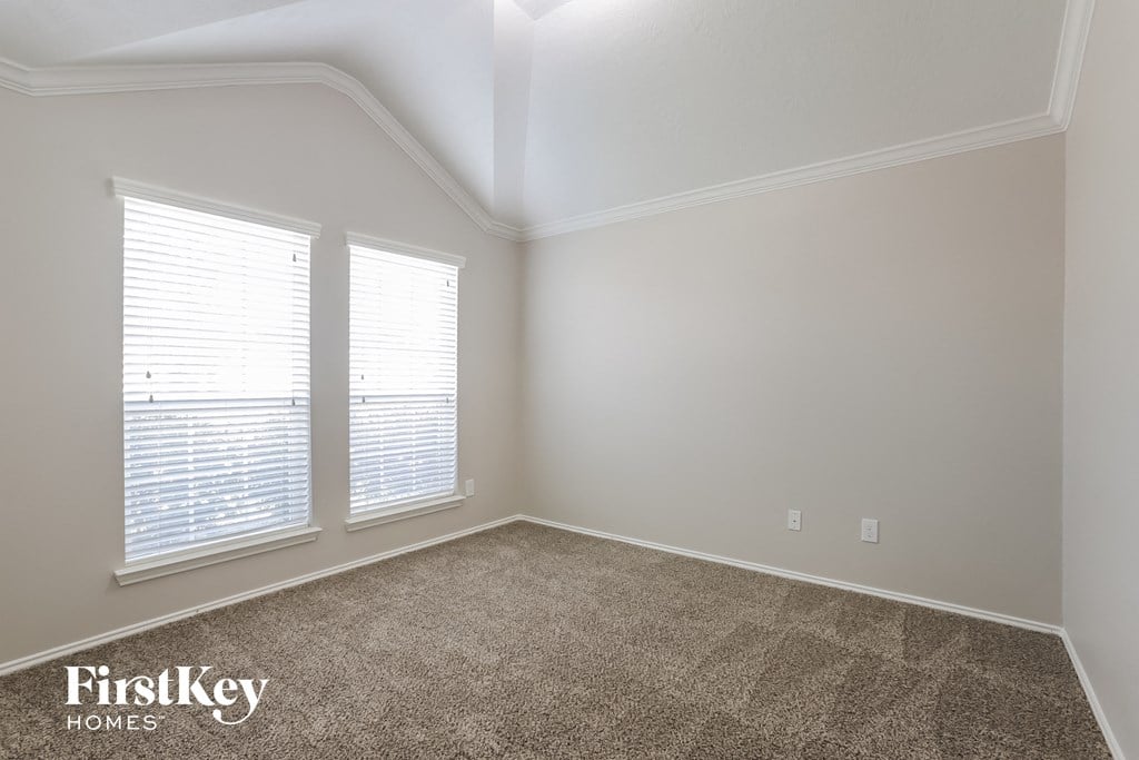 the second bedroom with two windows and a carpeted floor