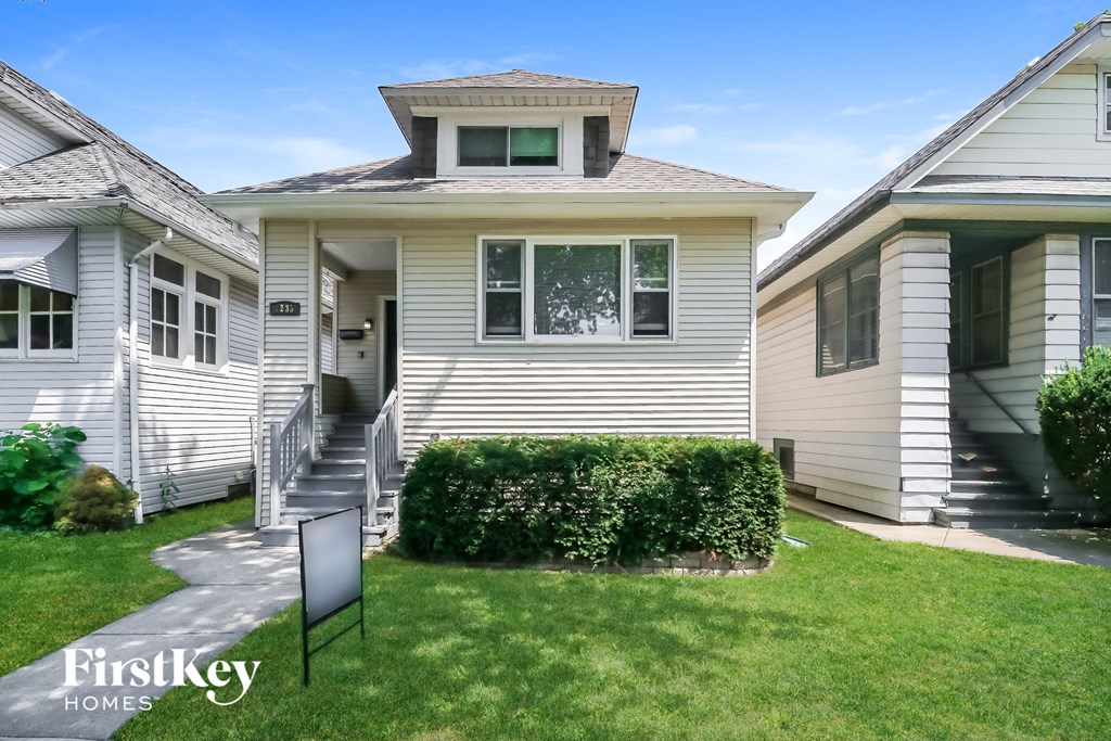 a white house with a yard and a black sign in front of it