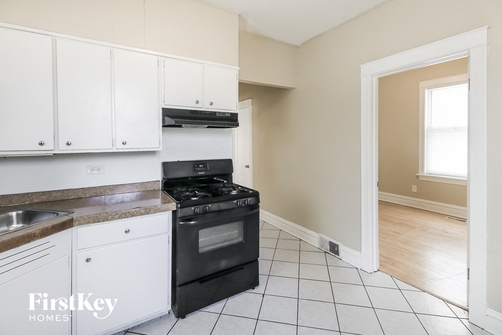 a kitchen with white cabinets and a black stove and oven