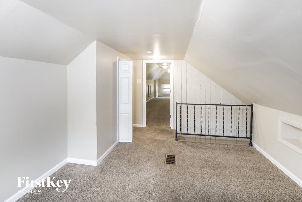 a hallway with a carpeted floor and white walls and a staircase