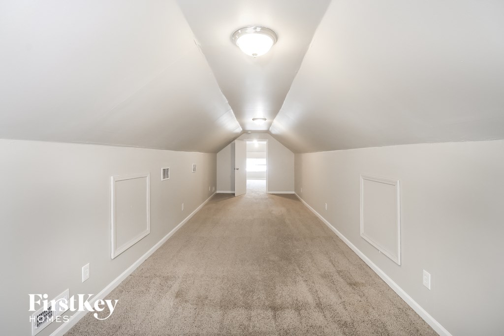 a room with a carpeted floor and white walls and a white ceiling and light