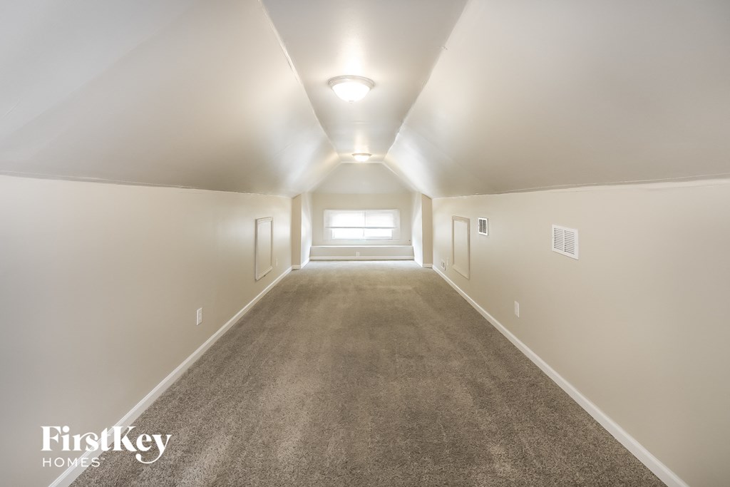 a large carpeted room with a window and a ceiling light