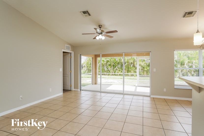 A spacious room with a ceiling fan and sliding glass doors leading to a garden.