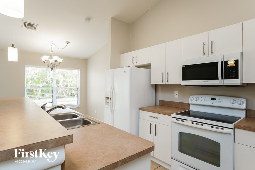 A kitchen with a wooden counter top and white cabinets.