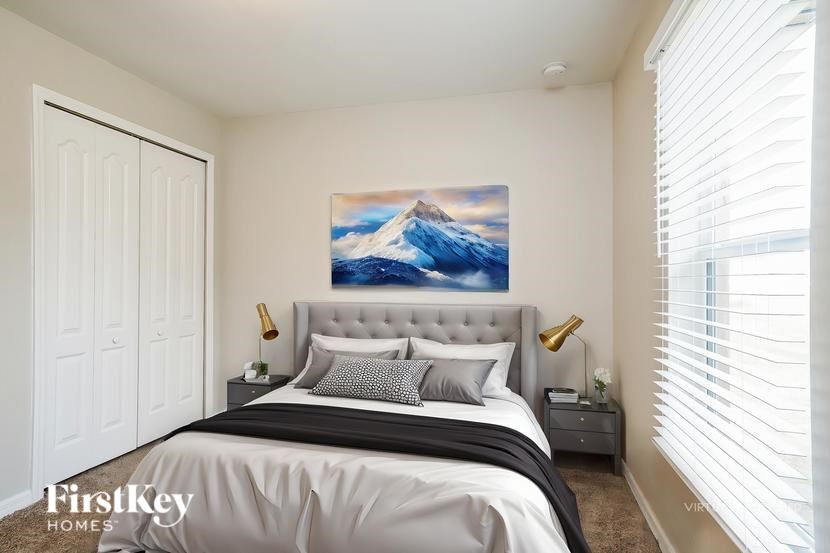 A bedroom with a large bed and a painting of a mountain scene on the wall.