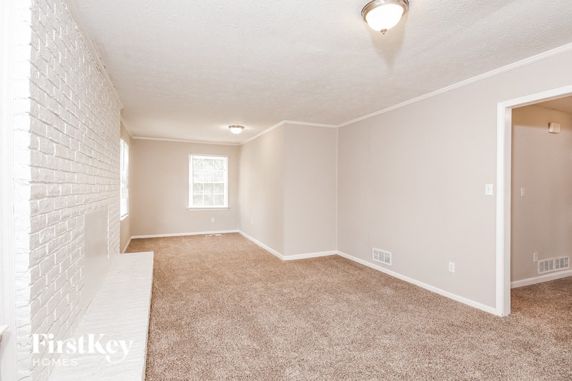 A spacious room with a carpeted floor and white walls.