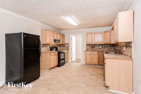 A kitchen with wooden cabinets and a black fridge.