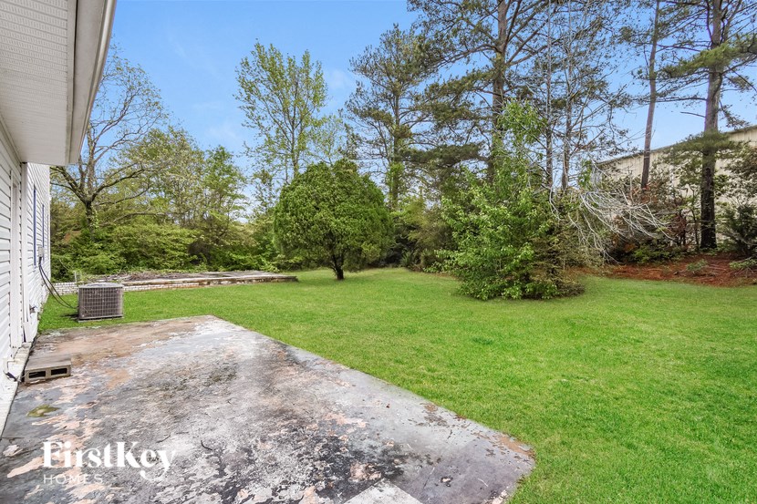 A backyard with a concrete patio and a grassy area.