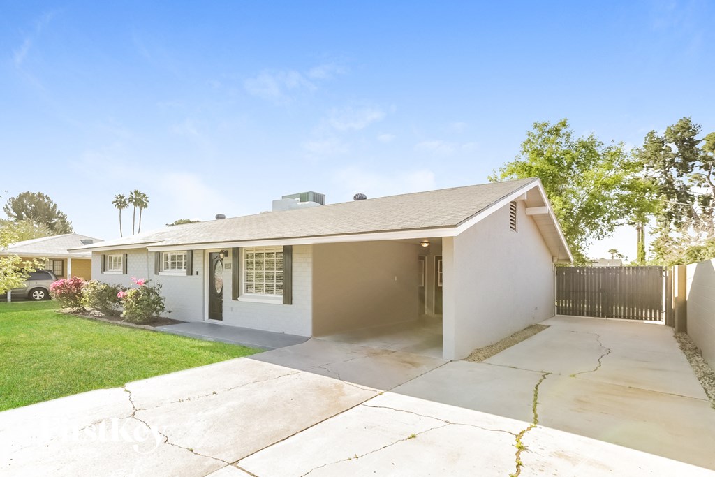 a white house with a driveway and a tree