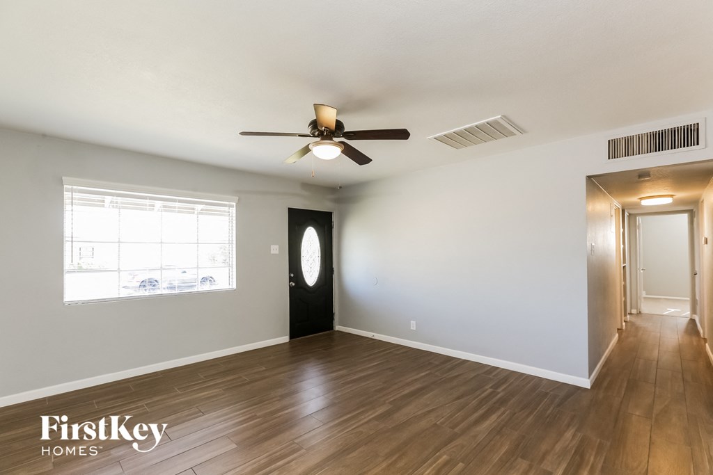 an empty living room with wood flooring and a ceiling fan