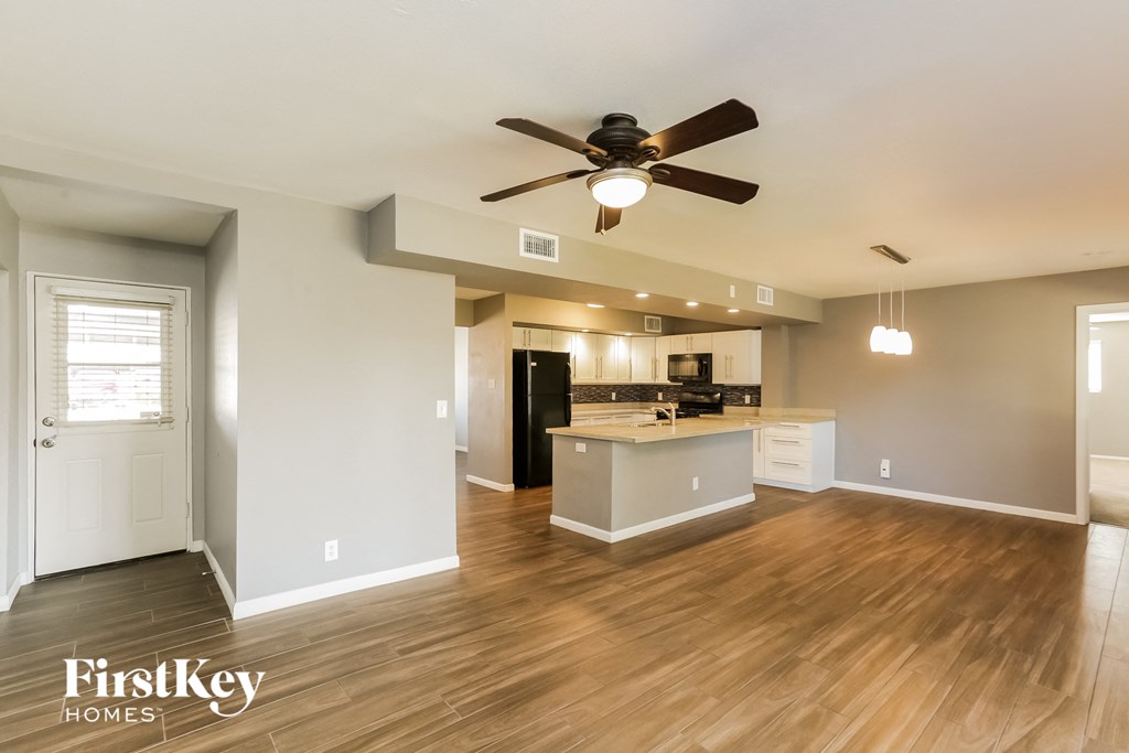 an open kitchen and living room with wood flooring and a ceiling fan