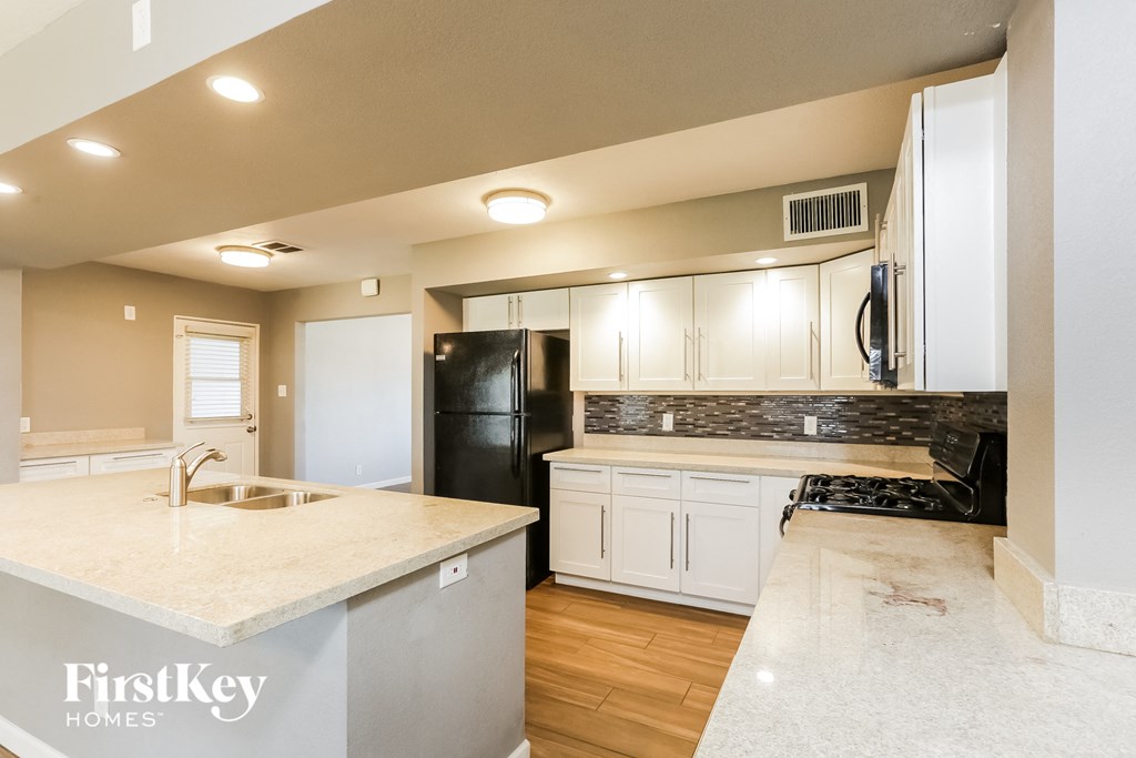 a kitchen with white cabinets and a black refrigerator